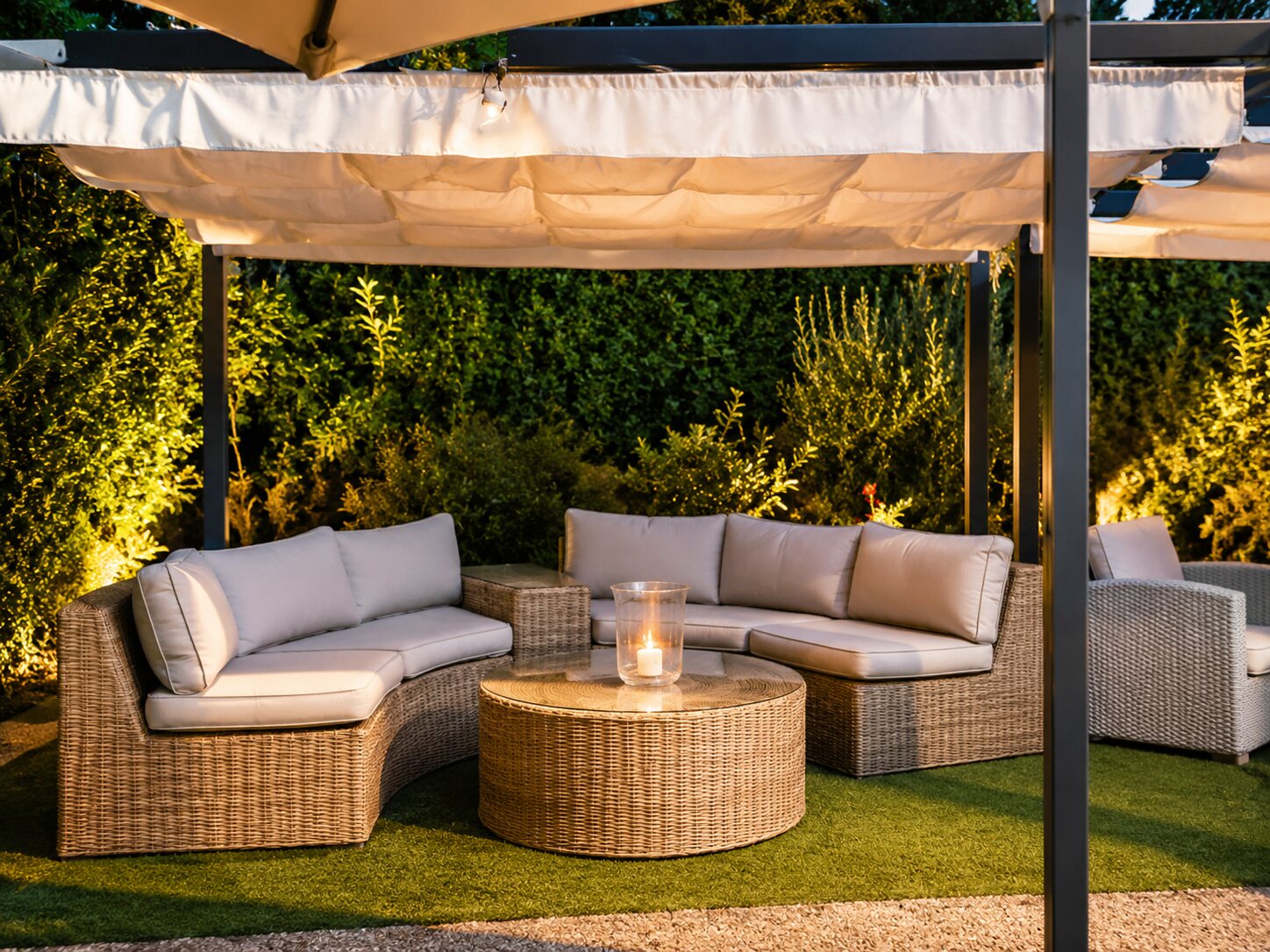 Angolo lounge in vimini sotto il pergolato, illuminato a candele