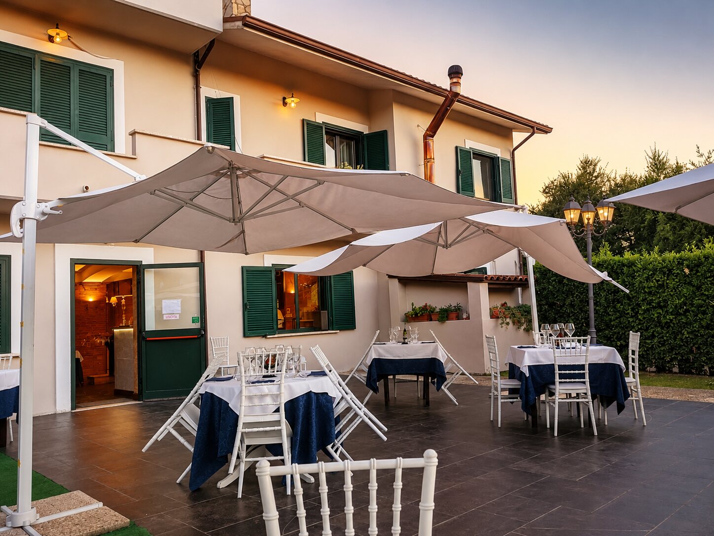 La terrazza esterna al tramonto, apparecchiata tra il verde